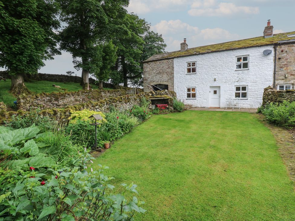 A garden with a house and stone wall at The LA'AL Cragg in Kirkby Stephen