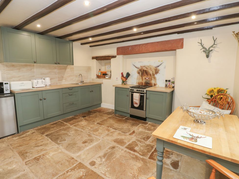 A kitchen with cabinets, stove, sink, and dining table at The LA'AL Cragg Kirkby Stephen