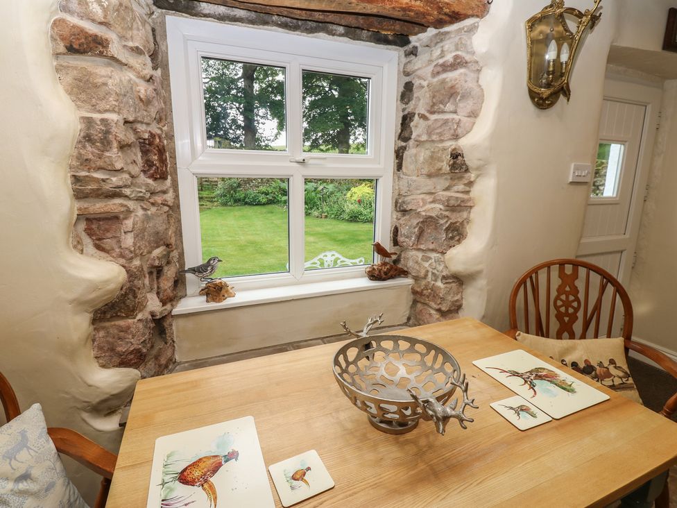 A dining room with a wooden table and window view at The LA'AL Cragg in Kirkby Stephen