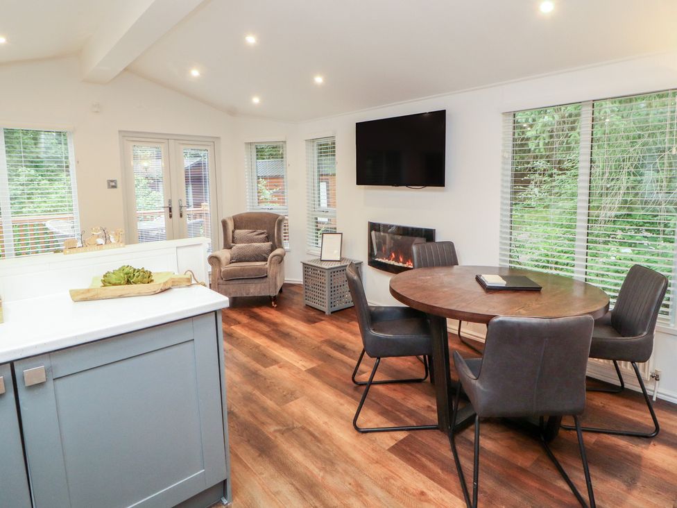 A dining room with a round table and chairs at Willows Lodge near White Cross Bay, near Windermere