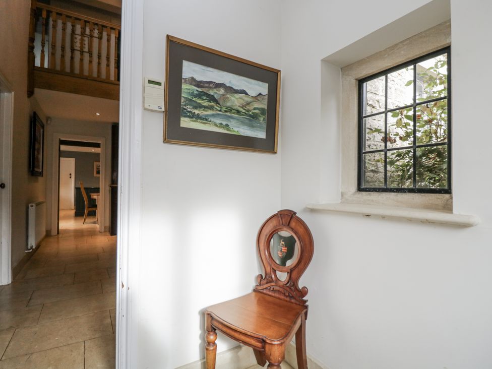 A hallway with a painting and chair at The Old Hall in Tetbury