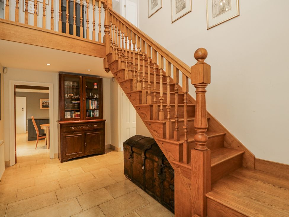 A hallway with a wooden staircase and cupboard at The Old Hall in Tetbury