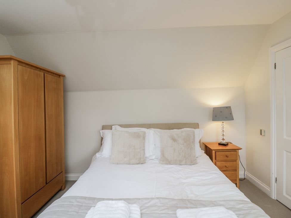 A bedroom with a bed, wardrobe, and bedside table at The Old Hall in Tetbury
