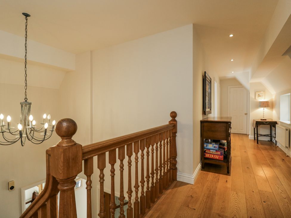 A hallway with a staircase and light fixtures at The Old Hall in Tetbury