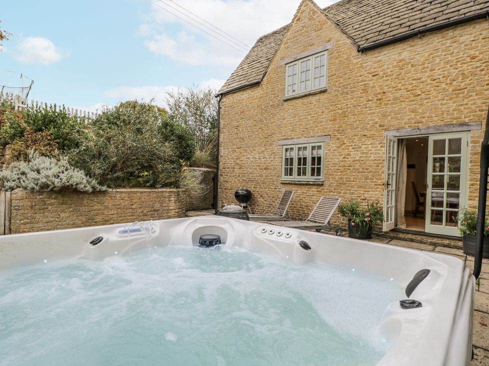 An outdoor area with a hot tub next to a house at The Old Hall in Tetbury