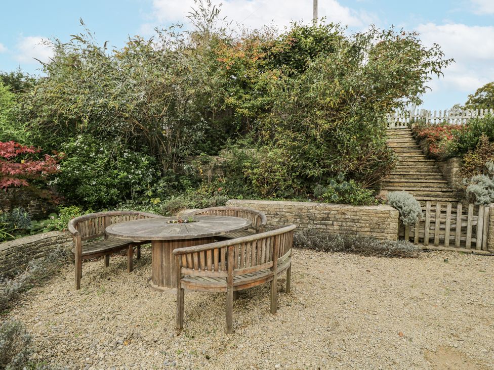 A garden with a wooden table and chairs at The Old Hall in Tetbury