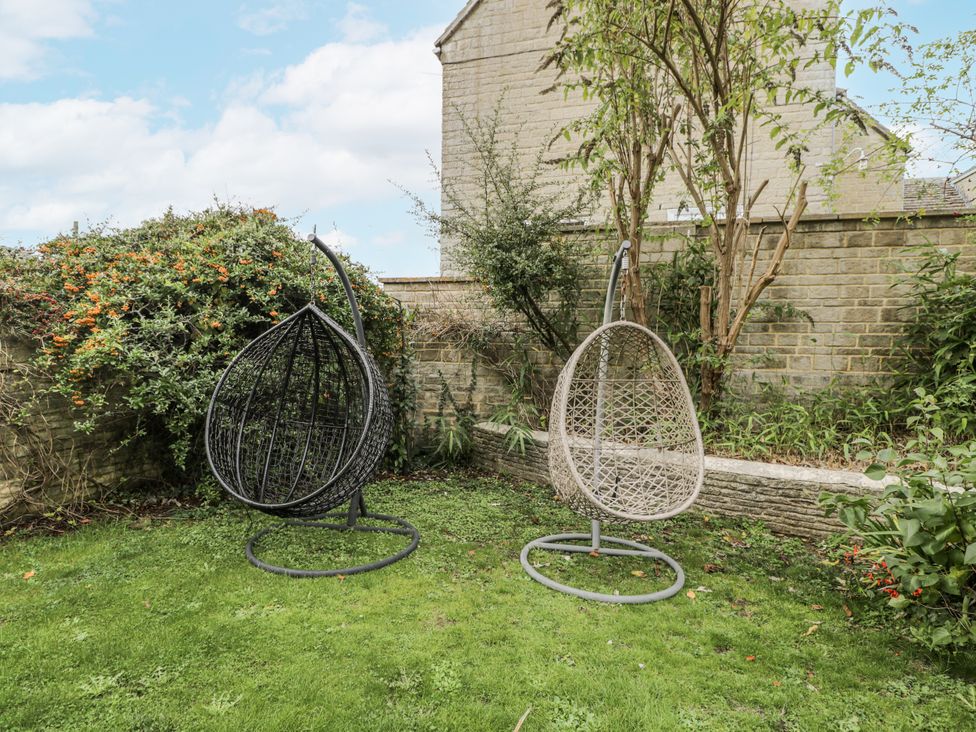 Two hanging chairs in a garden area at The Old Hall in Tetbury