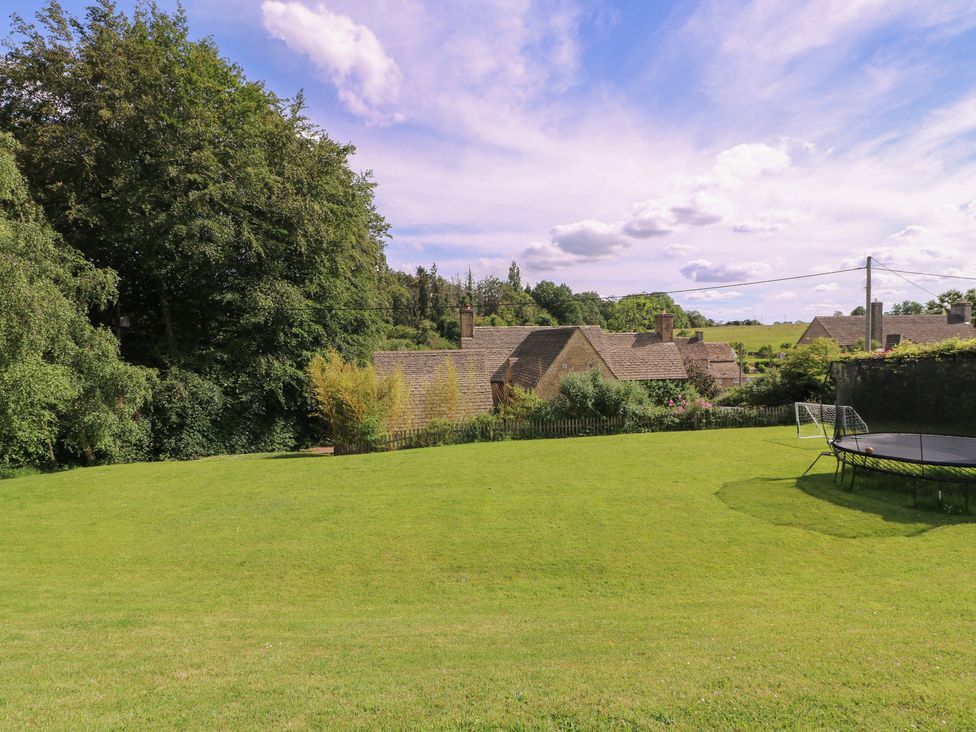 A garden with a trampoline and houses in the background at The Old Hall Westonbit Nr Tetbury