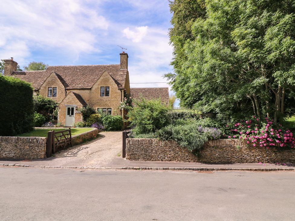 A house with a stone wall and flowers in the front yard at The Old Hall in Westonbit Nr Tetbury