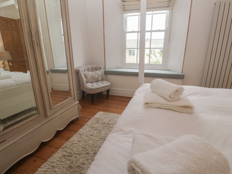 A bedroom with towels on the bed and an armchair at Scillonia in Penzance