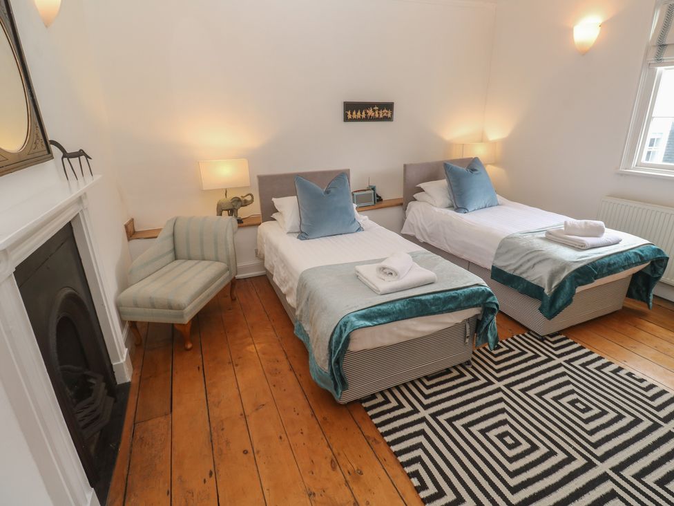 A bedroom with two beds and an armchair at Scillonia in Penzance