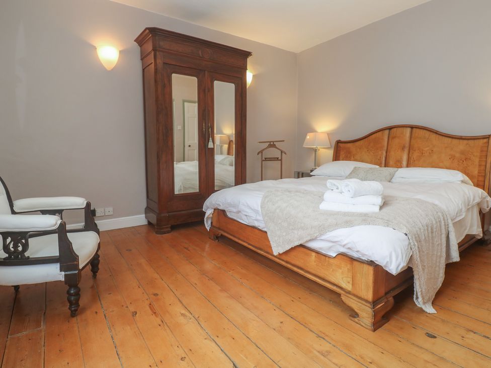 A bedroom with a wooden bed and wardrobe at Scillonia in Penzance