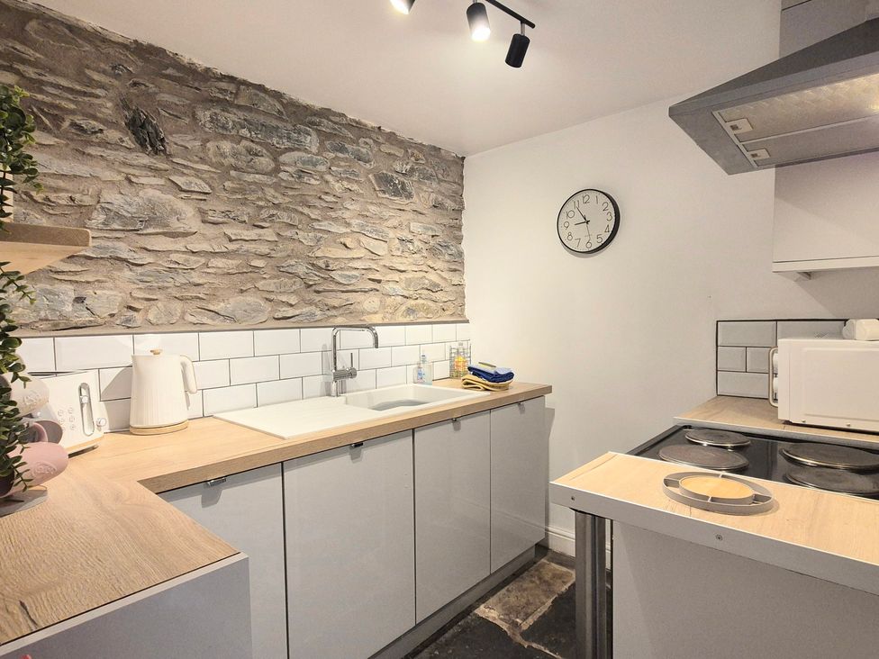 A kitchen with appliances and a stone wall at The Wonky Burrow in Bowness-On-Windermere
