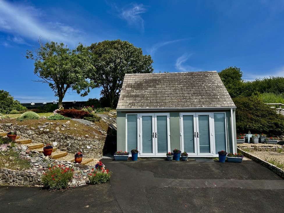 A shed with large windows and potted flowers at Tower Cottage Near Pembroke