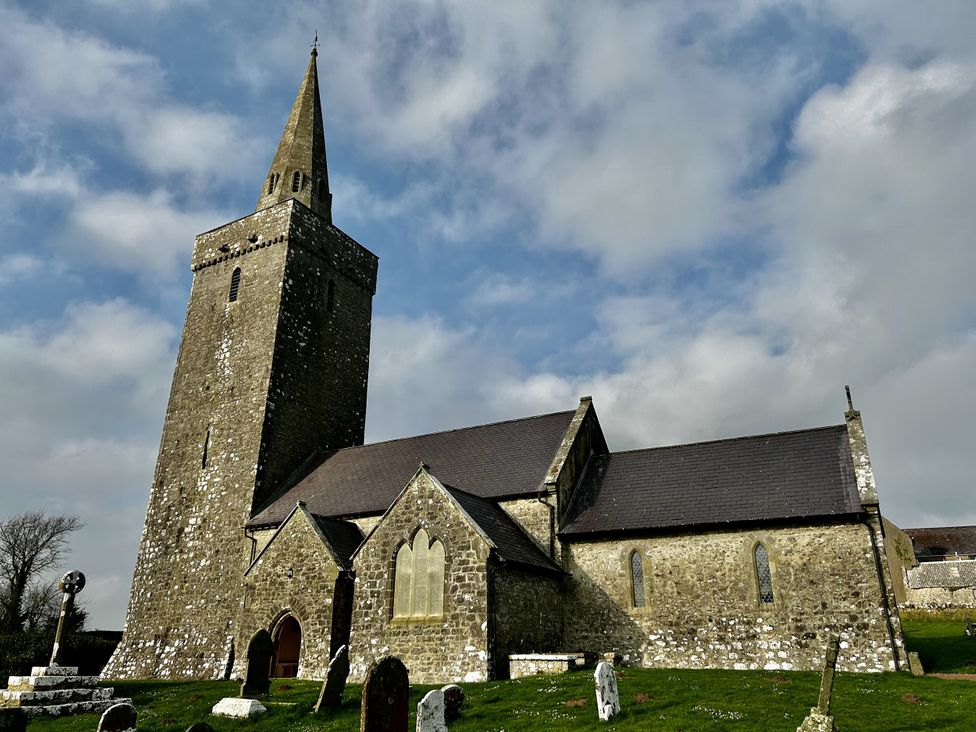 A church with a tower and gravestones near Pembroke at Tower Cottage