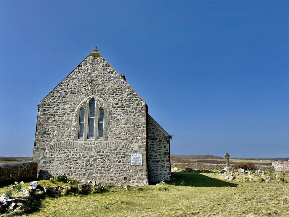 A stone church building with a cross on top at Tower Cottage near Pembroke