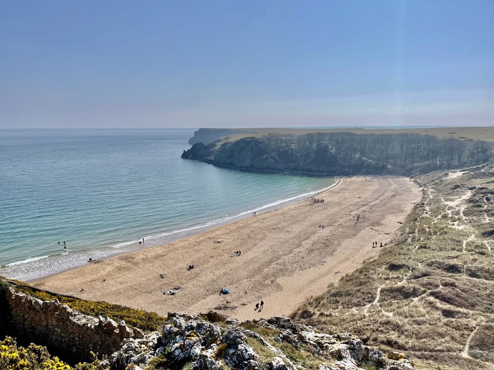 A beach with people walking near the water at Tower Cottage Near Pembroke