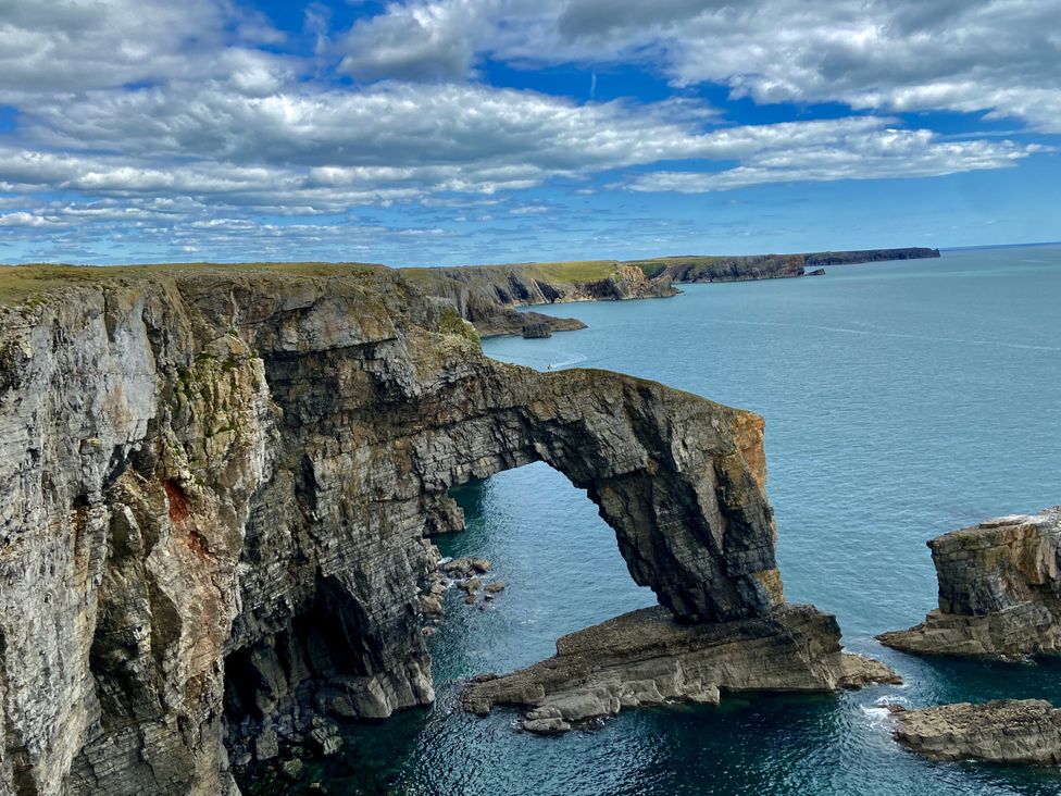 A cliff with an arch formation over the ocean at Tower Cottage Near Pembroke