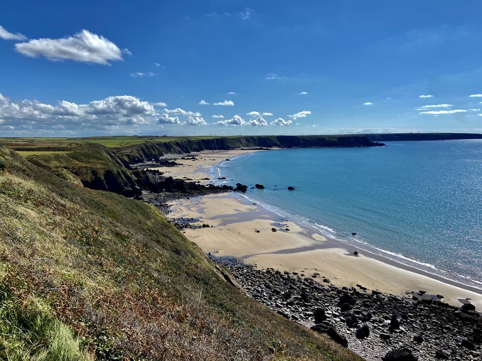 A beach with rocks and water under a blue sky at Tower Cottage near Pembroke