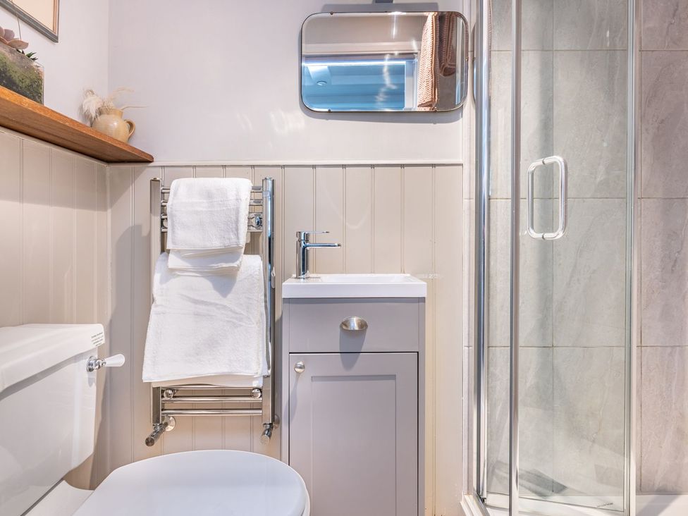 A bathroom with a sink, toilet, towel rack and shower at 14 Marine Parade Lyme Regis