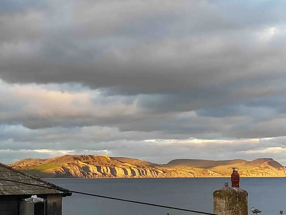 A view of hills and sea with clouds at 14 Marine Parade in Lyme Regis