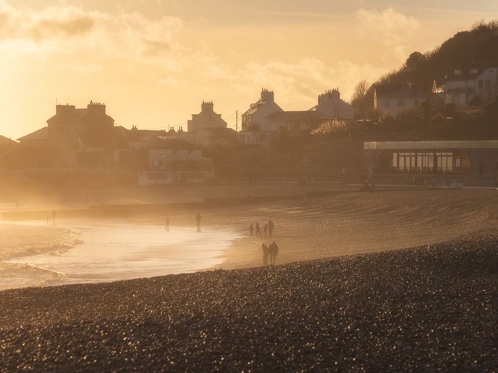 A beach with people walking and houses in the background at 14 Marine Parade Lyme Regis