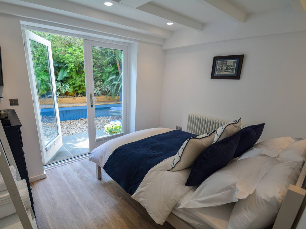 A bedroom with a bed and open door leading to a garden at Port House in Lyme Regis