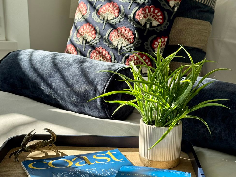 A living room with a plant and a magazine on a tray at Port House in Lyme Regis