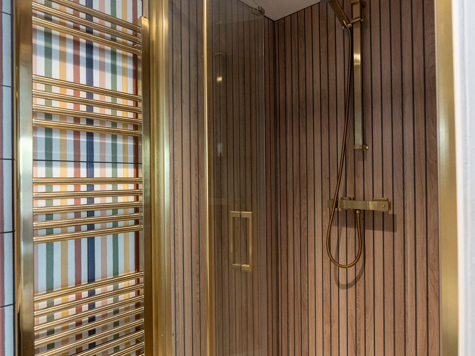 A shower with a gold shower head and heating ladder at Port House in Lyme Regis