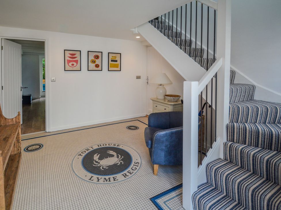 A hallway with stairs and artwork on the wall at Port House Lyme Regis