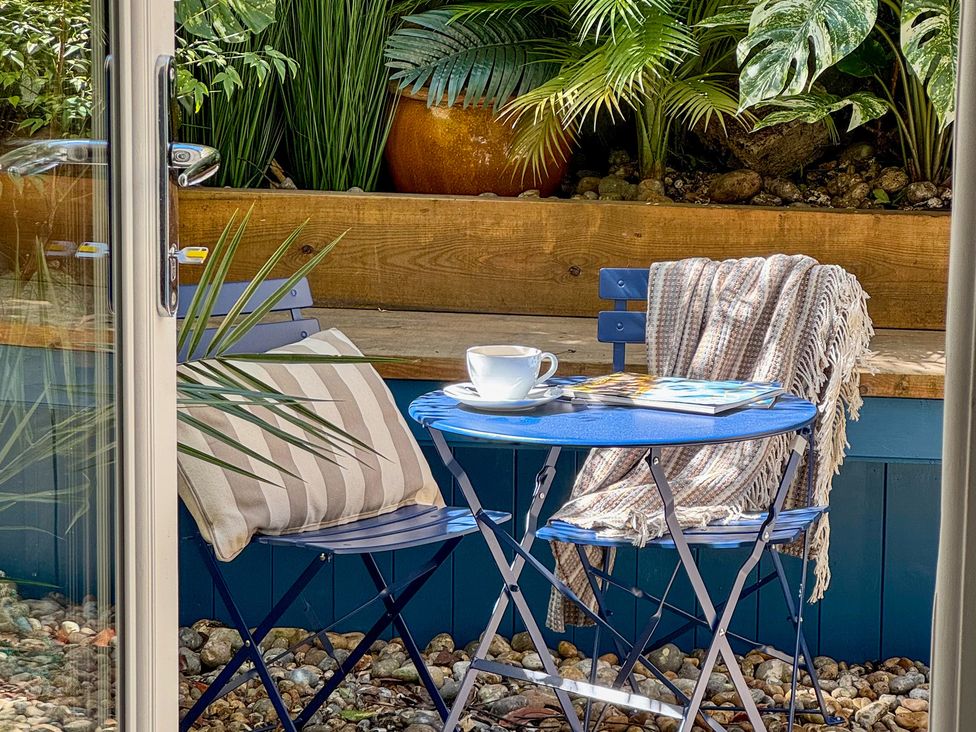 A garden setup with a blue table, chairs, and plants at Port House in Lyme Regis