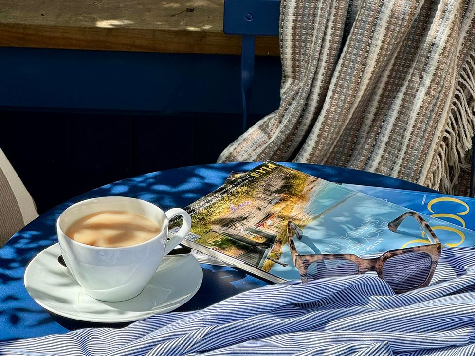 A coffee cup and magazine on a table in an outdoor seating area at Port House Lyme Regis