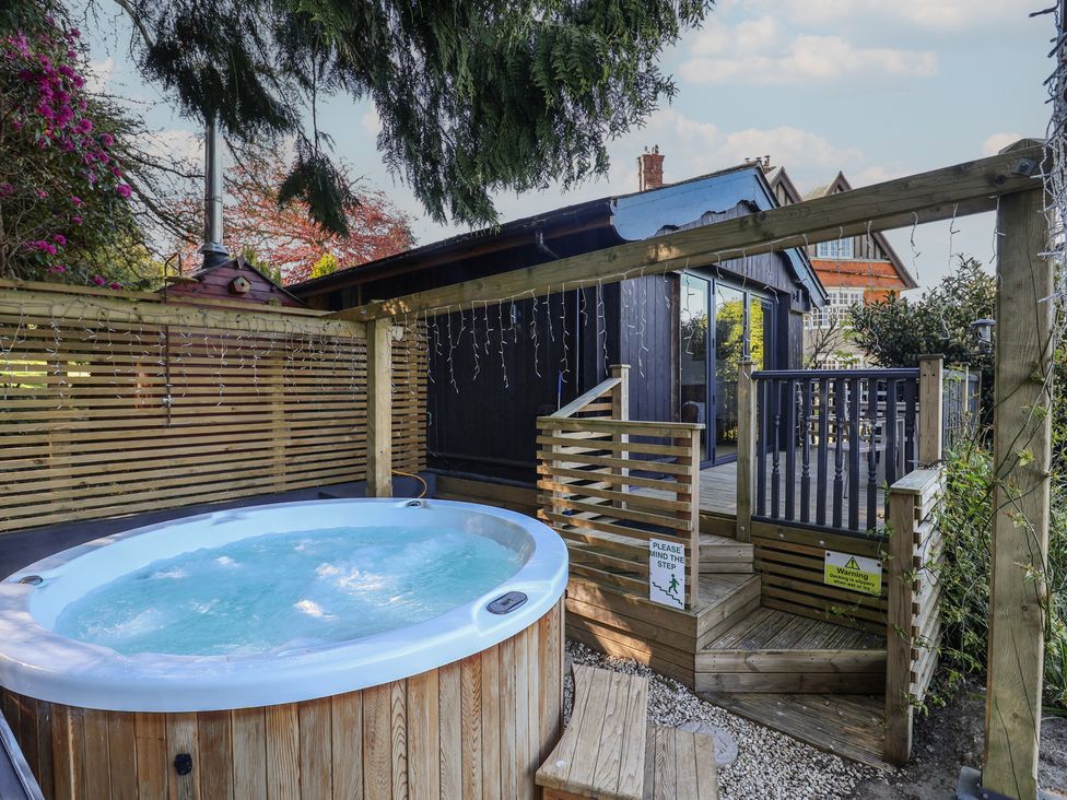 A hot tub next to wooden steps at Sir George Baker Cabin Uplyme