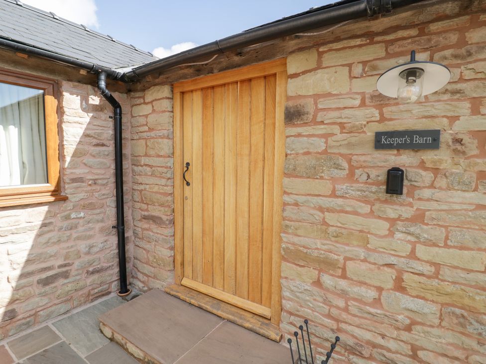An entrance with a wooden door and stone wall at Keepers Barn in Bromyard
