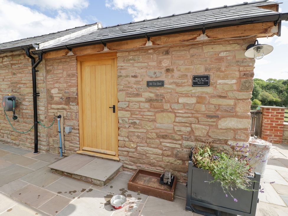 An outdoor area with a stone wall and a wooden door at Keepers Barn Bromyard
