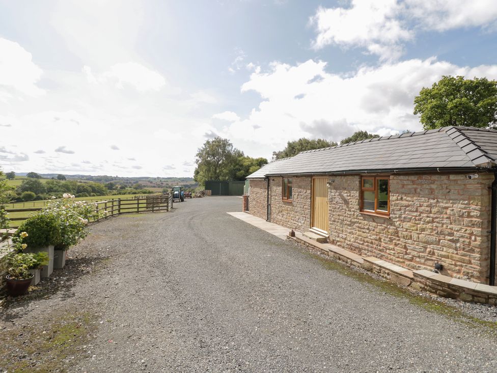 An outdoor view of a stone cottage with a gravel driveway at Keepers Barn Bromyard