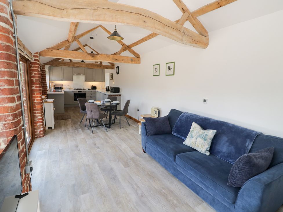 A living room with a sofa and dining area at The Cow Shed in Bromyard