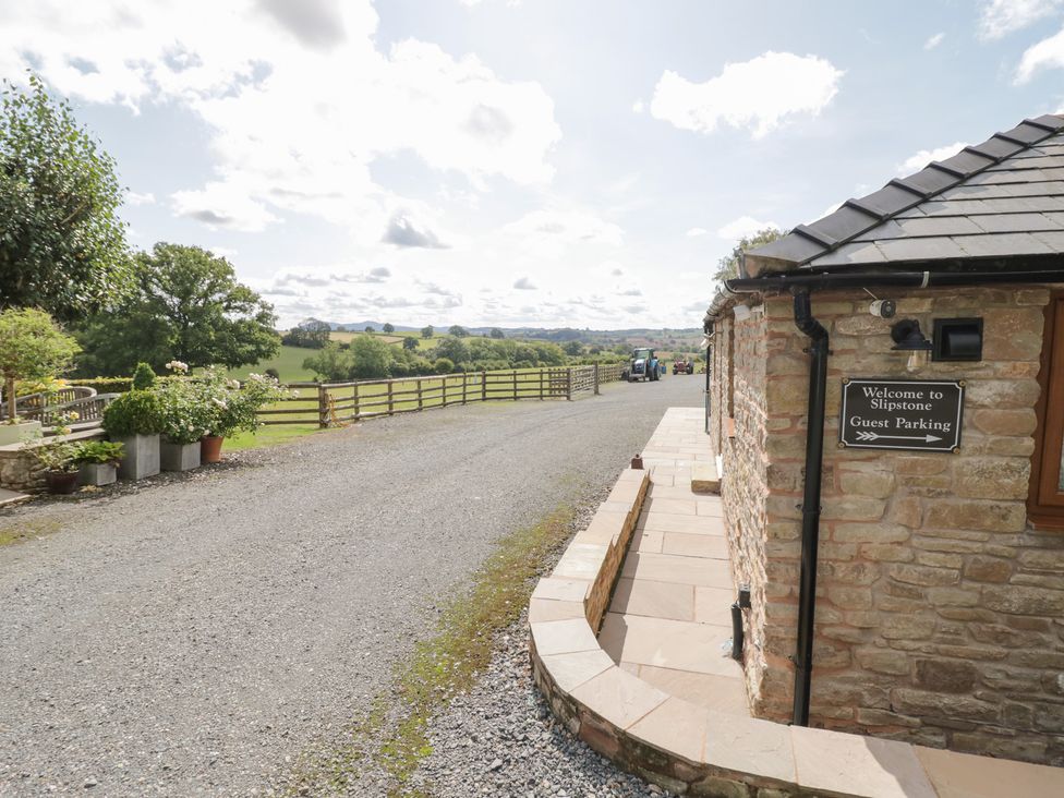 An outdoor area with a stone building and parking sign at The Cow Shed in Bromyard