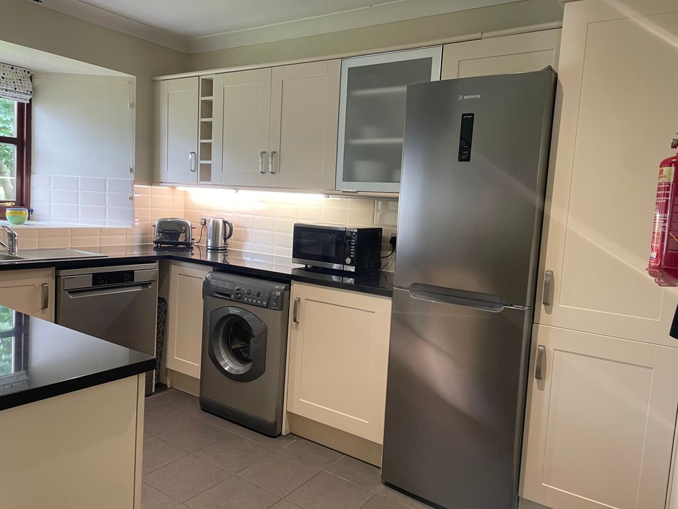 A kitchen with appliances including a fridge and washing machine at The Barn at Daldorch near Tarbolton