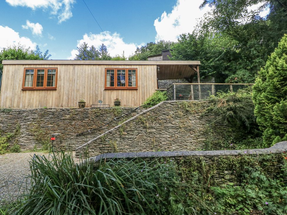 A wooden house with a stone wall and pathway at Ty Barddu in Cwmorgan near Newcastle Emlyn