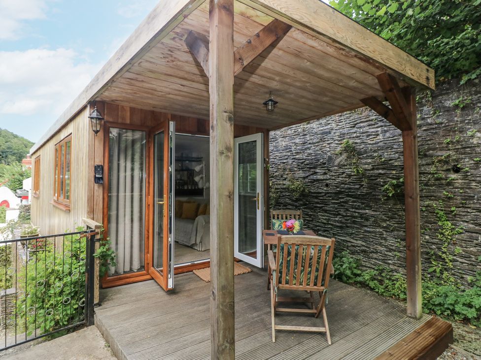 An outdoor seating area with a wooden table and chairs at Ty Barddu in Cwmorgan near Newcastle Emlyn