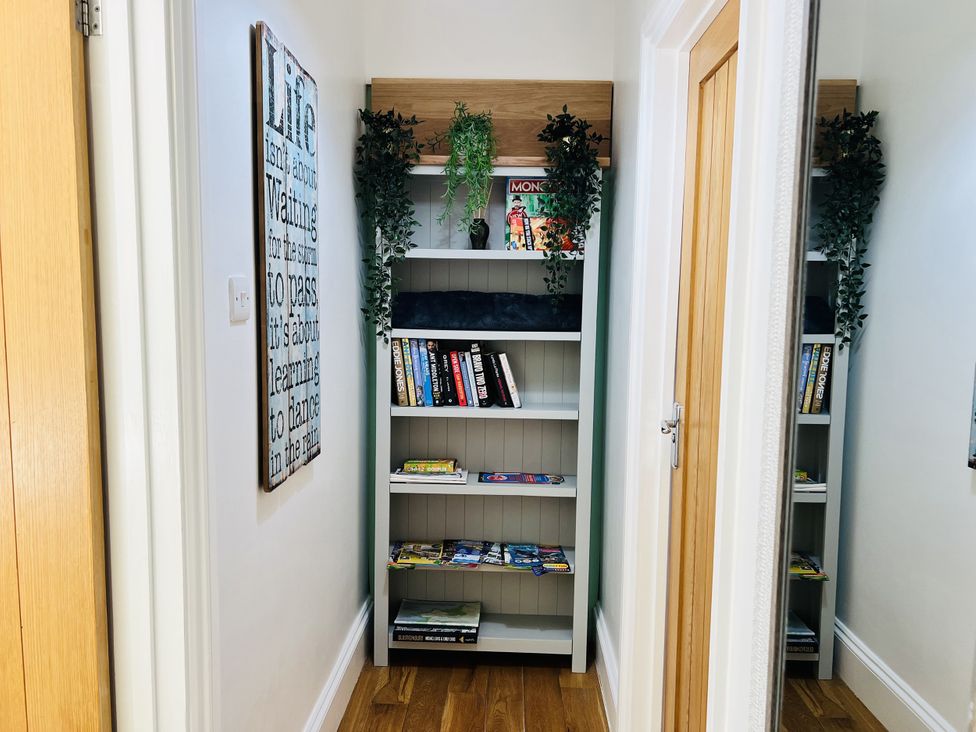 A hallway with a bookshelf and wall art at The Annexe Pentlepoir near Kilgetty