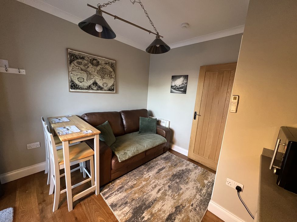 A snug with a sofa and table at The Annexe in Pentlepoir near Kilgetty