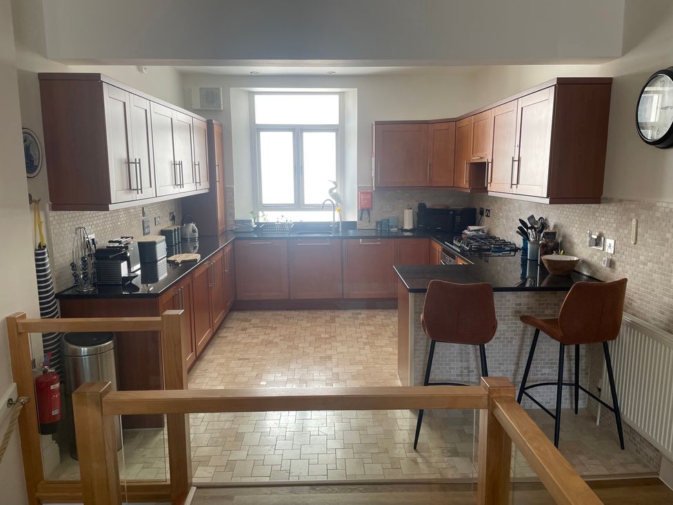 A kitchen with wooden cabinets and counter space at Hamnavoe in Stoke Fleming