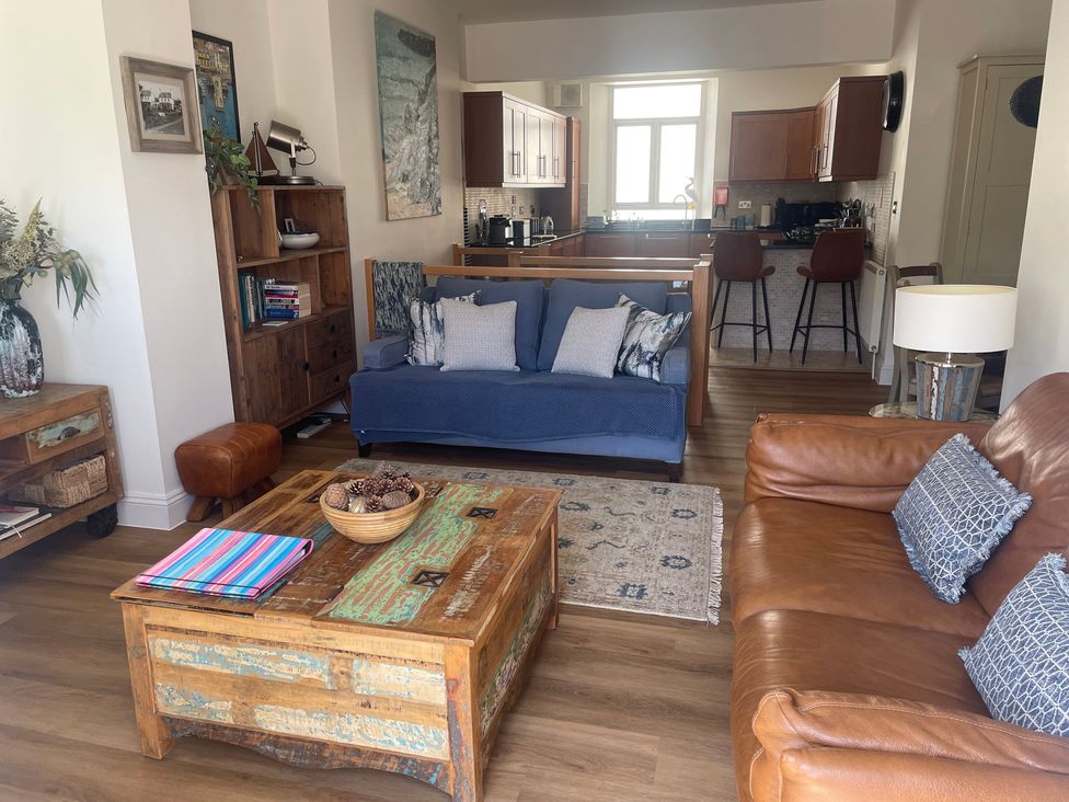 A living room with a sofa, coffee table, and bookshelf at Hamnavoe in Stoke Fleming