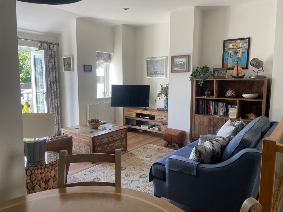 A living room with a sofa, coffee table, television and bookshelf at Hamnavoe in Stoke Fleming