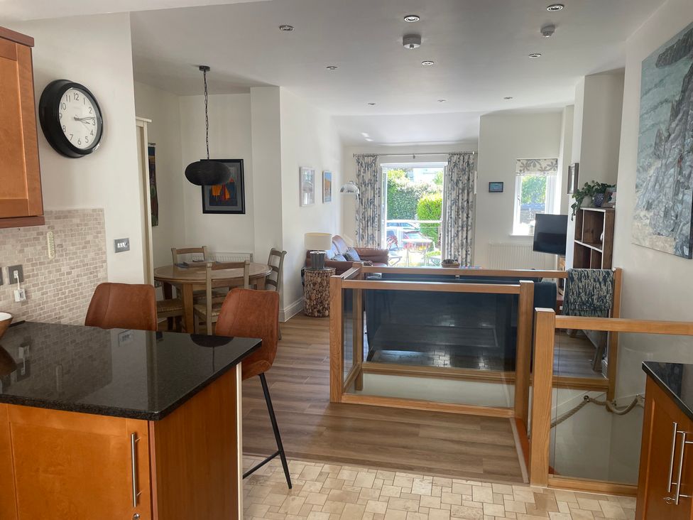 A living room with a dining area and kitchen view at Hamnavoe in Stoke Fleming
