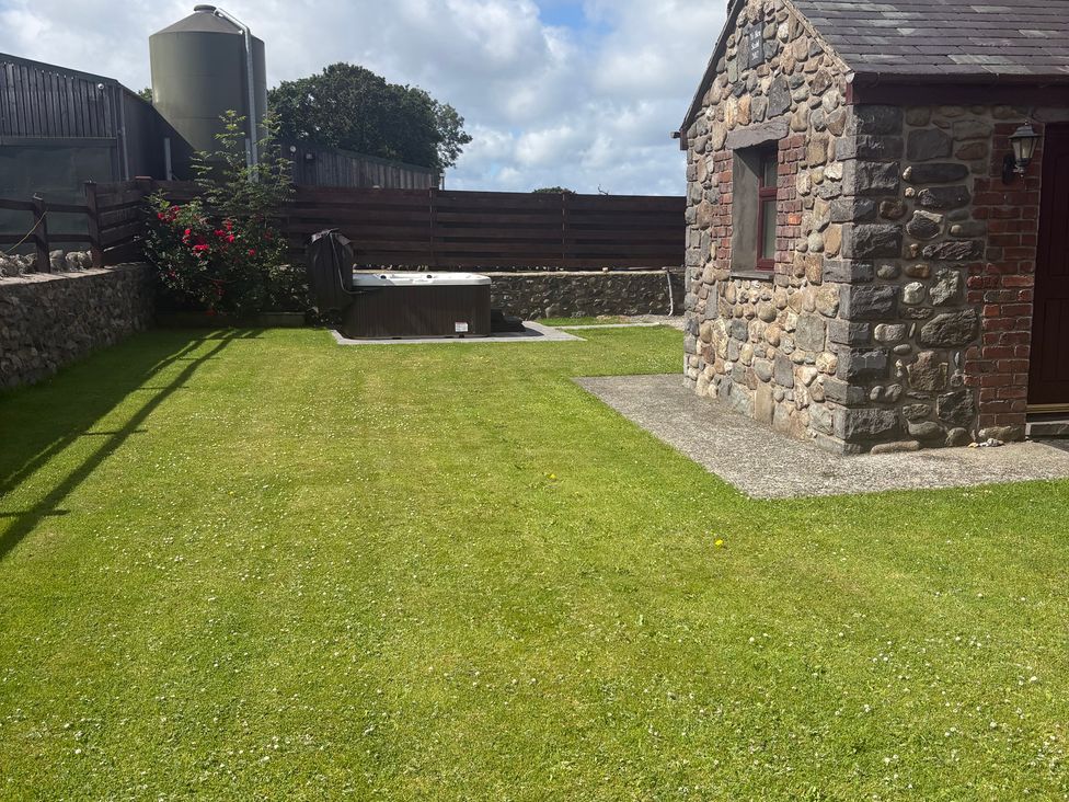A garden with grass and a hot tub at Yr Hen Stabl Llanwnda near Bontnewydd, Gwynedd