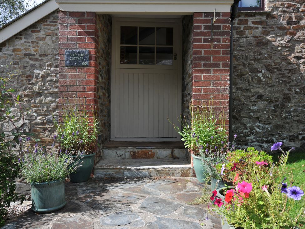 An entrance with a doorway and flower pots at Shipload Cottage in Hartland