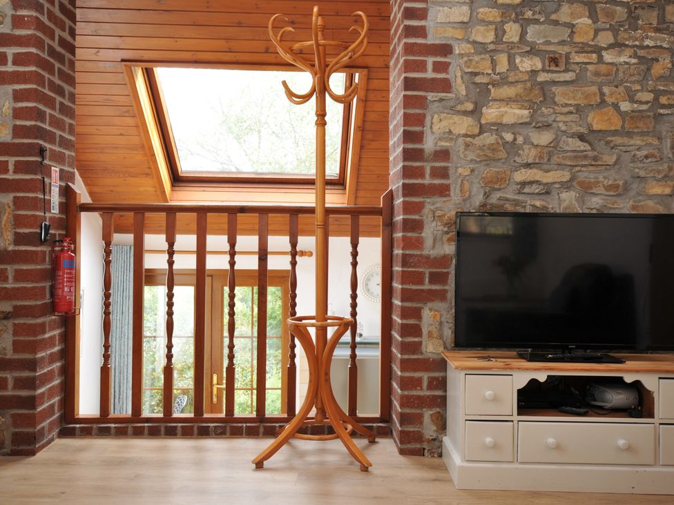 A living room with a coat rack and television at Shipload Cottage in Hartland